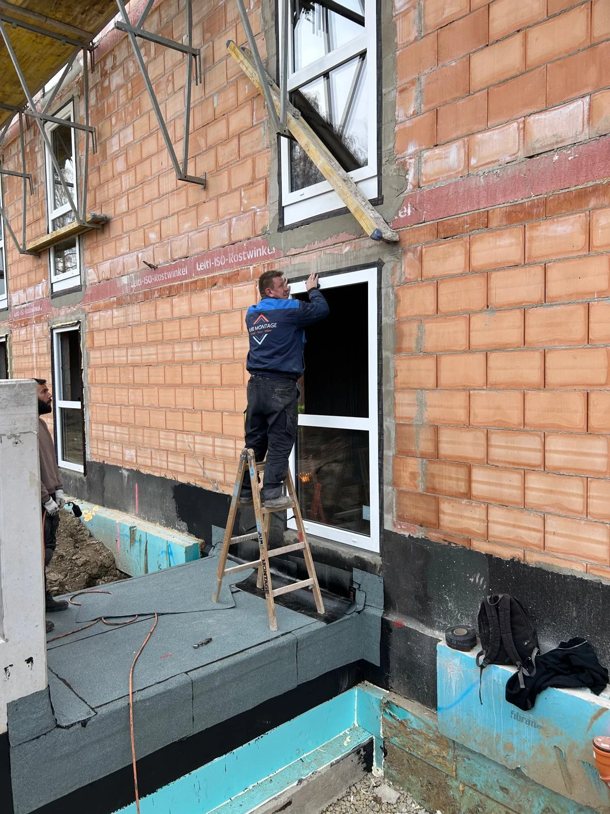 JURI MONTAGE Monteur auf einer Leiter bei der Fenstermontage außen am Mauerwerk