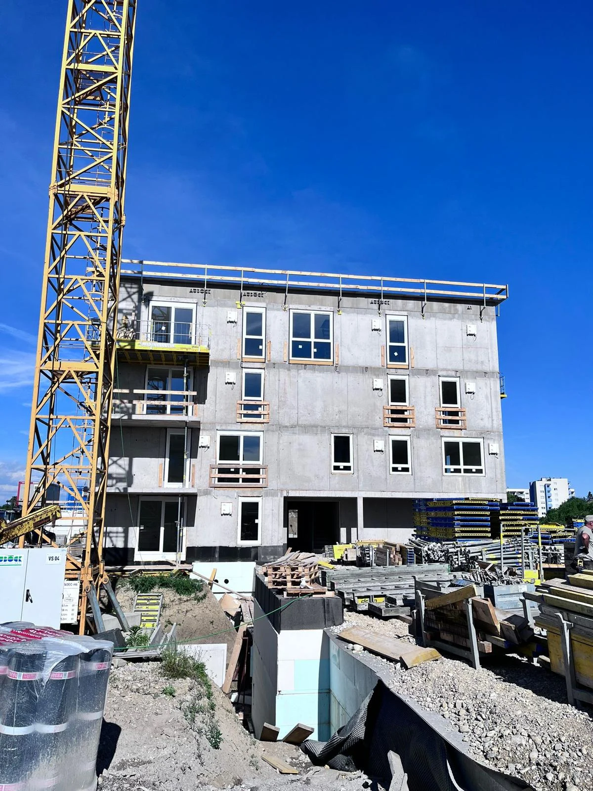 Neubau mit Fensterfront und gelbem Baukran