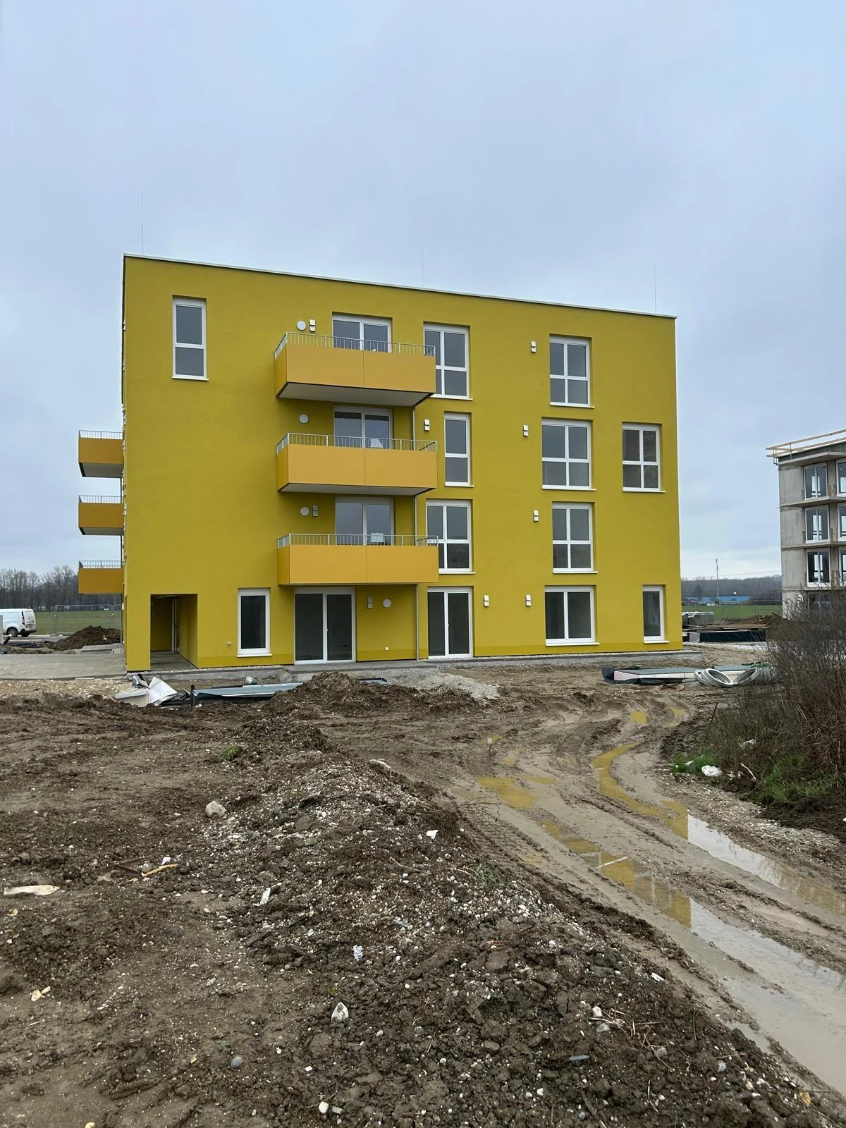 Gelbes Wohngebäude mit Balkonen und Fenstern während der Bauphase